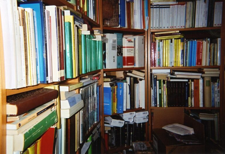 Books arranged vertically and in stacks on shelves in a personal library
