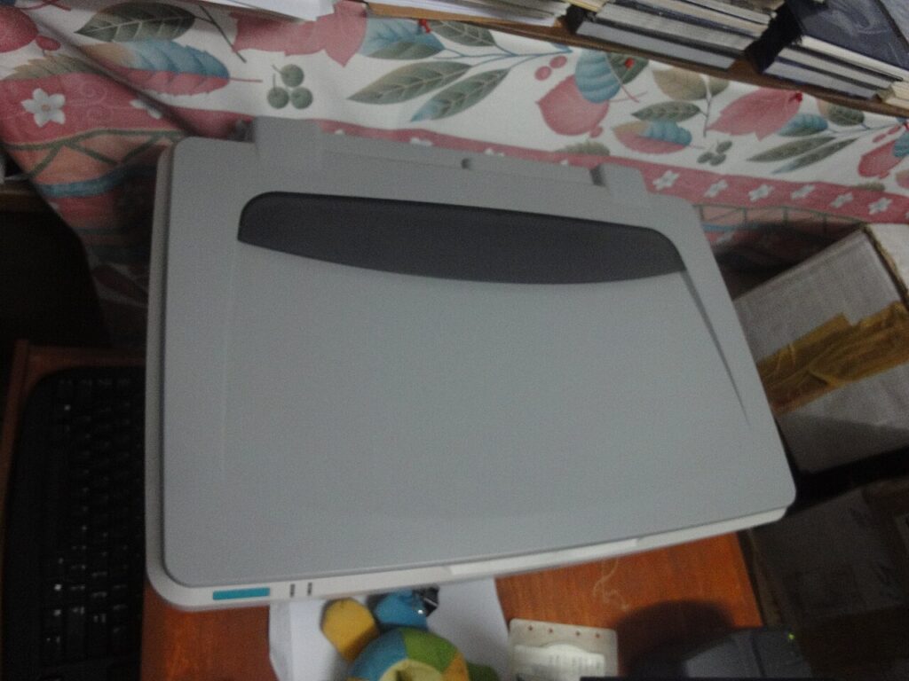 Closed flatbed scanner on a desk beside a keyboard