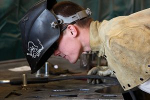 Mechanic inspecting metalwork at a workshop bench