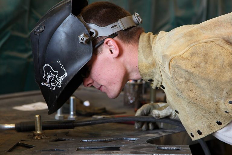 Mechanic inspecting metalwork at a workshop bench