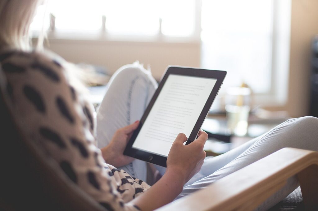 Person seated in a chair holding a tablet with text on its screen